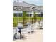 Outdoor dining area with black metal tables, white chairs, and striped umbrellas at 2280 Minfarm Way # 529, Mount Pleasant, SC 29466