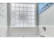 Bright bathroom featuring a glass block window allowing natural light and a white bathtub and tub surround at 366 Clayton Dr, Charleston, SC 29414