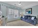 A light blue bedroom featuring a comfy blue couch, a desk, and a window at 366 Clayton Dr, Charleston, SC 29414