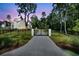 Exterior view of a charming white home with a long driveway behind an iron gate at 3864 Summerton St, Mount Pleasant, SC 29466