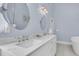 Bright bathroom with double sinks, oval mirrors, tile flooring and white cabinets at 45 Ocean Point Dr, Isle of Palms, SC 29451