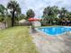 Backyard pool features mature palms, metal table with umbrella and ample space for entertaining at 715 Hampton St, Walterboro, SC 29488