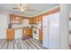 Galley kitchen featuring matching oak cabinets, white appliances, and modern LVP flooring at 7791 Peppercorn Ln, North Charleston, SC 29420