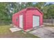 Durable red outbuilding with a roll-up door in fenced backyard at 7791 Peppercorn Ln, North Charleston, SC 29420