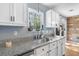 Close up of kitchen sink features granite countertop, white cabinets, and a window overlooking greenery at 7932 Riverbirch Ln, North Charleston, SC 29418