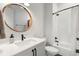 Bright bathroom features a white vanity with dark hardware and a round mirror with a wood trim at 8067 Jack Island Dr, Johns Island, SC 29455