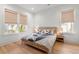 Inviting bedroom featuring hardwood floors, two windows, and a woven bed frame with stylish bedding at 8067 Jack Island Dr, Johns Island, SC 29455