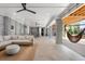 Spacious covered patio featuring a comfortable sectional sofa, hanging hammock chairs, and ceiling fans at 8067 Jack Island Dr, Johns Island, SC 29455