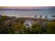Aerial view showcasing a waterfront property with private dock and distant cityscape views against a sunset sky at 939 White Point Blvd, Charleston, SC 29412