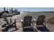 Waterfront view with boats docked near three wooden chairs on the dock, perfect for relaxing near the water at 102 Mariners Cay Dr, Folly Beach, SC 29439
