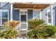 Close-up of the front door, framed by decorative palm trees and a covered porch at 1070 Moss Grove Dr, Moncks Corner, SC 29461