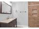 Bathroom featuring dark vanity, decorative mirror, sink, and a tiled shower with a niche at 1117 Oceanview Rd, Charleston, SC 29412