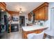 Well-lit kitchen with warm wood cabinetry, contrasting black appliances, and a cozy breakfast bar at 112 Ravenswood Ct, Summerville, SC 29485