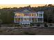 Elegant coastal home with multiple levels, a deck, and lush greenery at sunset at 1136 Ocean Forest Ln, Seabrook Island, SC 29455