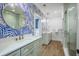 A full bathroom featuring dual sink vanities, decorative wallpaper, and a stand-up shower with glass door at 1174 Hitchfield Ln, Awendaw, SC 29429