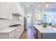 A kitchen with white cabinets, stainless steel appliances, and an island with seating and beverage refrigerator at 1174 Hitchfield Ln, Awendaw, SC 29429