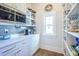 Walk-in pantry with white cabinets, open shelves, and small window at 1174 Hitchfield Ln, Awendaw, SC 29429