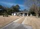Well-maintained white brick home with a long driveway, green trees, and a spacious front yard at 1344 Pickett St, Charleston, SC 29412