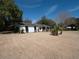 Wide shot of a white brick ranch-style home surrounded by a large yard and mature trees at 1344 Pickett St, Charleston, SC 29412