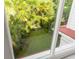 View of the backyard oasis framed by a window, showcasing lush greenery and landscaping creating a private retreat at 21 Limehouse St, Charleston, SC 29401