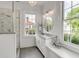Bright bathroom with a marble-topped vanity, open shower, and large windows offering views of the surrounding neighborhood at 21 Limehouse St, Charleston, SC 29401