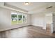Bright bedroom featuring white trim, tray ceiling, hardwood floors, and multiple windows at 210 Quimby Hill Dr, Huger, SC 29450