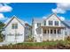 Charming white two-story home with a two-car garage and inviting front porch on a sunny day at 3019 Eventide Dr, Johns Island, SC 29455