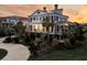 Elegant two-story home with symmetrical design, black shutters, red roof and landscaped yard at sunset at 3232 Pignatelli Cres, Mount Pleasant, SC 29466