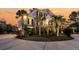 A beautiful two-story home with a circular driveway and professionally landscaped yard with tall palm trees at sunset at 3232 Pignatelli Cres, Mount Pleasant, SC 29466