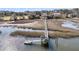 Picturesque waterfront scene with a dock extending into the marsh, surrounded by lush greenery and distant homes at 3232 Pignatelli Cres, Mount Pleasant, SC 29466