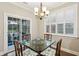 Bright dining room features chandelier, shuttered windows, and glass top table for four at 5358 Birdie Ln, Hollywood, SC 29449