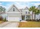 Charming two-story home with light gray siding, front porch, white trim, a two car garage and manicured front lawn at 5358 Birdie Ln, Hollywood, SC 29449
