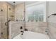 Elegant bathroom showcasing a soaking tub and tiled shower with a glass partition and window at 5358 Birdie Ln, Hollywood, SC 29449