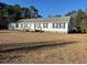 Single-story home featuring black shutters, a welcoming front porch, and a small carport at 60 Caboose Ct, Cottageville, SC 29435