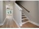 Open staircase design with wood-look flooring, neutral walls, and a simple wood railing in the foyer at 6273 Ballpark Rd Rd, Hollywood, SC 29449
