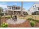 Spacious backyard with a stone patio, lush landscaping, and lovely home exterior in the background at 8661 Refuge Point Cir, North Charleston, SC 29420