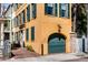 View of the corner of a yellow home with green shutters and an attached garage, showcasing the unique architecture at 92 Bogard St, Charleston, SC 29403