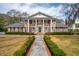 Charming brick home with classic white columns, manicured landscaping, and a inviting walkway at 12 Broughton Rd, Charleston, SC 29407
