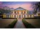 Stunning two-story brick home featuring stately white columns, classic shutters, and manicured landscaping at twilight at 12 Broughton Rd, Charleston, SC 29407