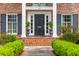 Charming brick home entrance featuring manicured landscaping, classic black door and sidelight windows at 12 Broughton Rd, Charleston, SC 29407
