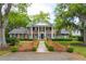 Classic brick home showcasing symmetrical design, white columns, and manicured landscaping at 12 Broughton Rd, Charleston, SC 29407