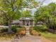 Stately brick home featuring classic columns, black shutters and lush landscaping at 12 Broughton Rd, Charleston, SC 29407
