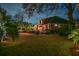 A spacious backyard is illuminated at dusk, highlighting the manicured lawn and exterior brick home at 1208 Wynnwood Ct, Mount Pleasant, SC 29464