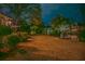 Expansive backyard featuring mature trees, manicured lawn, and a tranquil pond reflecting the home's lights at night at 1208 Wynnwood Ct, Mount Pleasant, SC 29464