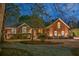 Charming brick home with manicured landscaping, inviting entrance, and warm exterior lighting at dusk at 1208 Wynnwood Ct, Mount Pleasant, SC 29464