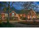 Elegant brick home at dusk with illuminated windows, lush landscaping, and a inviting walkway at 1208 Wynnwood Ct, Mount Pleasant, SC 29464