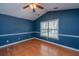 A primary bedroom with blue walls, hardwood floors, a ceiling fan, and a window at 140 Moon Shadow Ln, Summerville, SC 29485