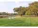 Scenic backyard with lush green lawn, mature trees, and three Adirondack chairs overlooking the water at 2416 Kings Gate Ln # 403, Mount Pleasant, SC 29466