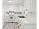 A view of an all-white vintage kitchen with white appliances and gray wood-look flooring at 28 Elmora Ave, Goose Creek, SC 29445