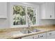 Bright kitchen featuring a stainless steel sink, granite countertop, white cabinets, and a window with a green tree view at 2837 Baywood Dr, Seabrook Island, SC 29455